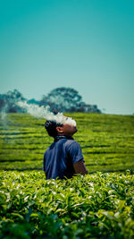 Man emitting smoke while standing amidst plants