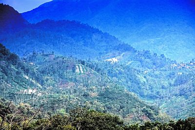 High angle view of land and mountains against blue sky