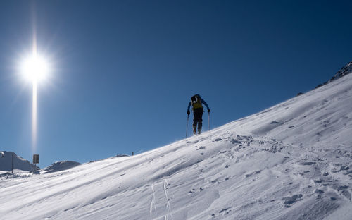 People on snowcapped mountain against clear sky during winter