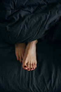 Women's legs stick out from under the covers in bed