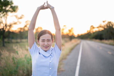 Portrait of smiling girl standing on road against sky