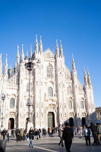 Group of people in front of cathedral against clear blue sky