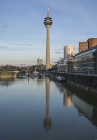 River in front of rheinturm tower in city against sky