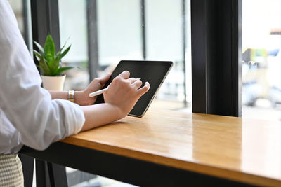 Midsection of woman using digital tablet on table