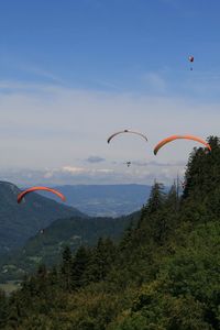 Parapenters flying over mountain against sky