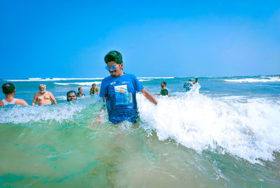 People enjoying in swimming pool against sea