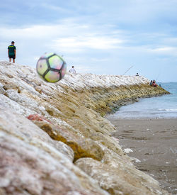 Rear view of man standing at beach against sky