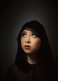 Portrait of beautiful young woman against black background