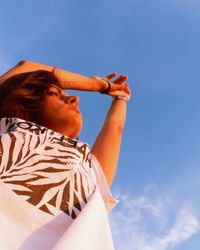 Low angle view of girl holding blue sky