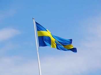 Low angle view of flag against blue sky