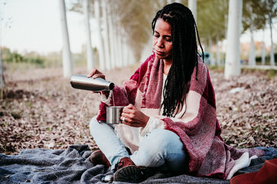 Young woman looking away while sitting on land