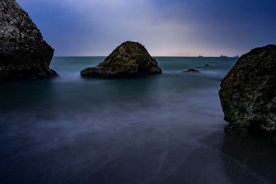 Scenic view of rocks in sea against sky