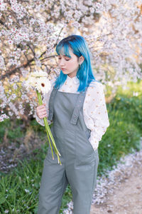 Young woman standing by cherry blossom