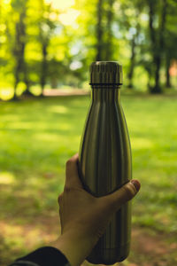 Close-up of unrecognizable female hand holding water bottle. reusable steel thermo water bottle in
