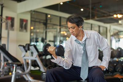 Mature man lifting dumbbell in gym