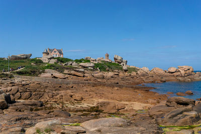 Rock formations by sea against clear blue sky