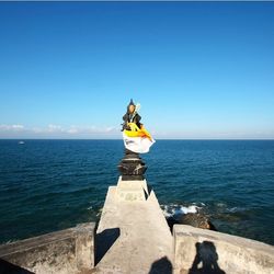 Woman standing by sea against clear blue sky