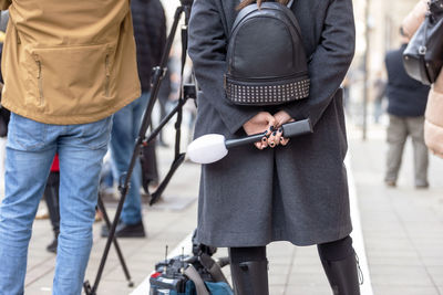 Rear view of man holding umbrella standing on footpath