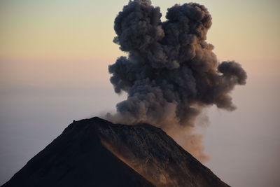 Smoke emitting from volcanic mountain against sky