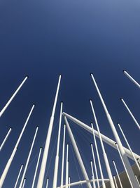 Low angle view of poles against clear blue sky