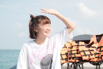 Portrait of a smiling young woman against sea