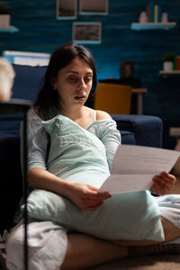 Woman reading document while sitting at home