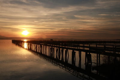 Pier over sea against sky during sunset