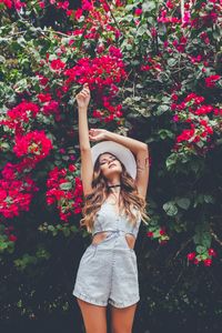 Full length of woman standing by pink flowering plants