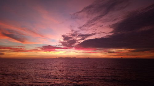 Scenic view of sea against dramatic sky during sunset