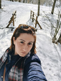 Portrait of woman covering face on snow covered land