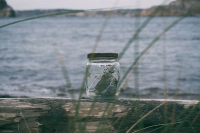 Close-up of glass bottle against sea