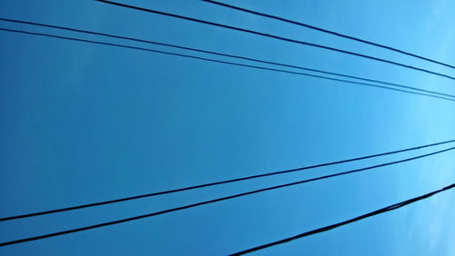 Low angle view of power cables against blue sky