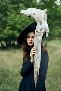 Portrait of woman standing by tree trunk