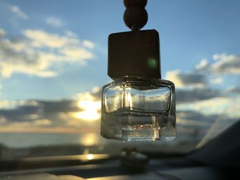 Close-up of glass bottle against sky