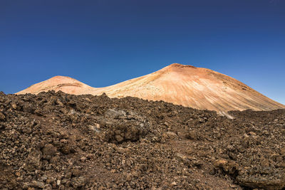 Scenic view of arid landscape against clear blue sky