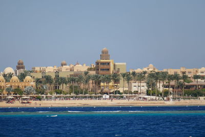 Buildings by sea against clear sky