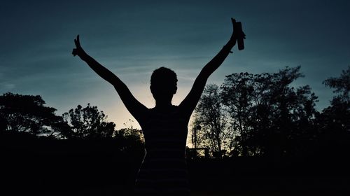 Silhouette person by tree against sky