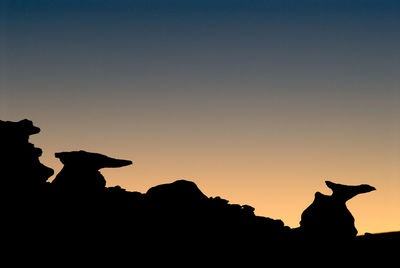 Silhouette rock formation against clear sky during sunset
