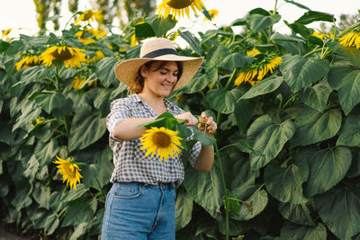 Beautiful young woman with sunflowers enjoying nature and laughing on summer sunflower field.