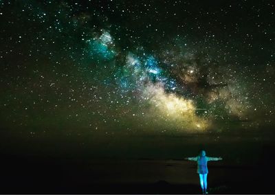 Rear view of woman standing against star field at night