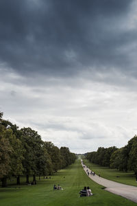 Footpath amidst trees at windsor castle against cloudy sky