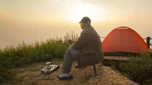 Rear view of man sitting at tent against sky