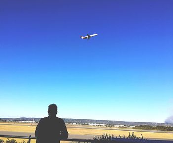 Airplane flying over beach against clear blue sky