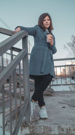 Portrait of woman standing against railing