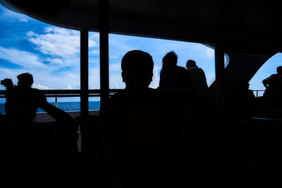 Silhouette people against sky seen through window