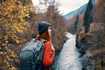 Young woman looking away against trees during autumn