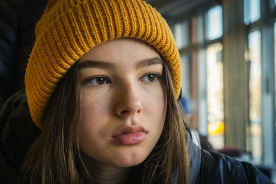 Pensive teenager girl in a knitted hat indoors