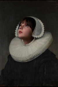 Portrait of young woman standing against black background