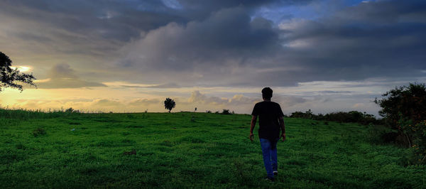 Rear view of man standing on field against sky