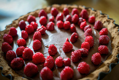 Delicious full chocolate tart with several raspberry on top, close up of fruit cake dessert 